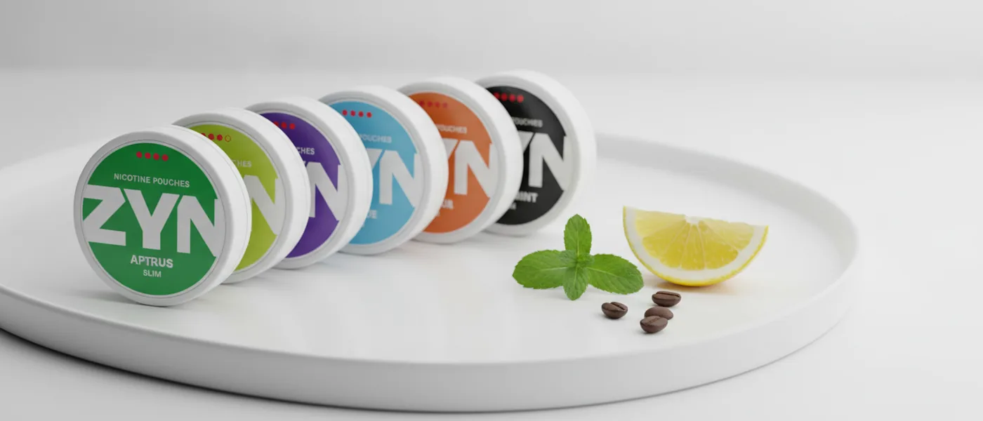 A fan of ZYN nicotine pouch cans on a clean white tray with mint, lemon and coffee beans